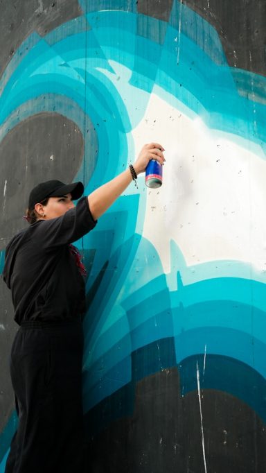 Een persoon spuit kleurrijke graffiti op een muur met een spuitbus.